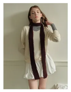 Detail of burgundy wool blend skinny scarf styled with a cream knit sweater and mini skirt