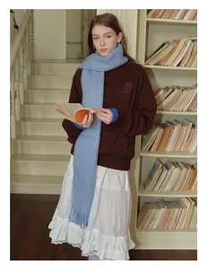 Dettaglio di sciarpa in misto alpaca mohair azzurro con frange e felpa marrone
