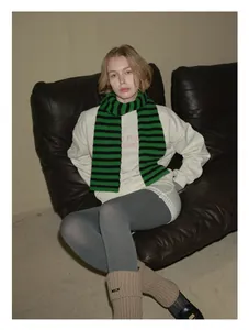 Detailed view of green and black striped 100% wool scarf paired with casual loungewear