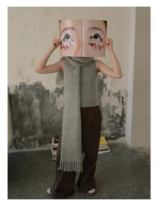 Detail shot of a grey wool scarf with fringes and textured knit vest in a chic outfit