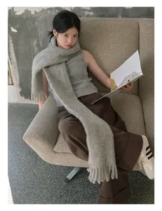 Detail shot of a thick grey wool scarf with long tassels on a textured fabric sofa