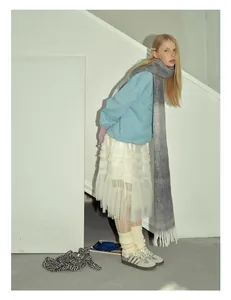 Dettaglio di sciarpa in misto lana sfumata con maglione azzurro e gonna di pizzo bianco
