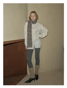 Winter outfit detail featuring striped wool scarf and ivory sweatshirt with red printing