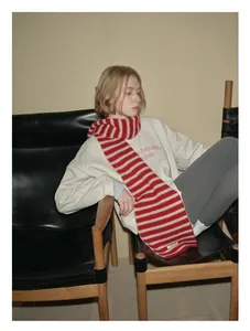 Detail of red and white striped 100% wool scarf featuring a fine knit texture and brand label