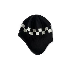 Black and white checkerboard knit earflap beanie with ribbed texture on white background