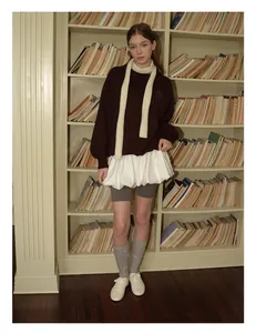 Nahaufnahme eines weichen beigen Strickschals kombiniert mit einem Vintage-College-Outfit