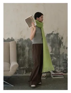 Bright green wool scarf with long tassel details styled in a modern industrial setting