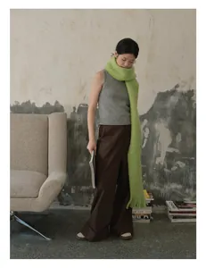 Detail shot of a soft grass green wool scarf with long tassels over a grey knit top