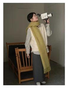 Detail of mustard green wool scarf with long tassels paired with cream knitted vest