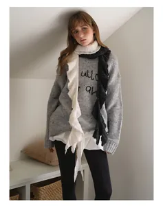 Detail of grey wool knit sweater with ruffled collar and black linear embroidery