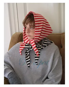 Gros plan d'un foulard triangle en laine rayé porté avec un pull gris pour le style d'hiver
