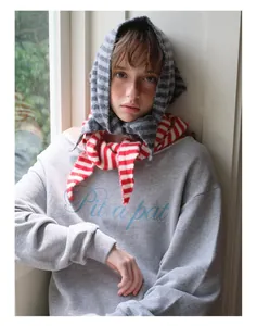 Détail d'une écharpe triangle en laine rayée rouge et blanc avec un sweat-shirt gris