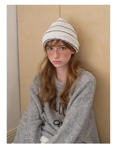 Close-up of soft striped knit beanie and gray textured sweater for autumn winter style