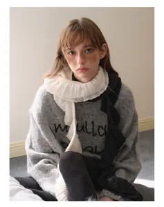 Detailed texture of grey wool blend knit sweater with decorative white ruffled scarf