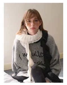 Detail of gray sweater with embroidered text and wavy ruffle wool blend scarf