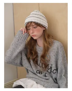 Detailed view of the soft knitted beanie with black stripes and gray sweater texture