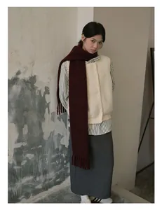 Detail of wool blend fringed scarf in deep red layered with a knit vest and striped shirt