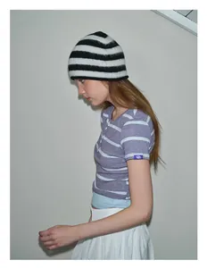 Detail of a striped knit beanie and short-sleeve shirt with a purple logo tag on the sleeve