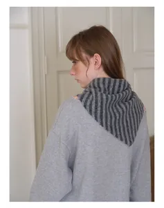 Détail de l'écharpe rayée en laine portée avec un sweat gris pour un look automne décontracté