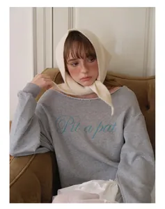 Détail d'un foulard triangle en maille de laine crème douce noué autour du cou