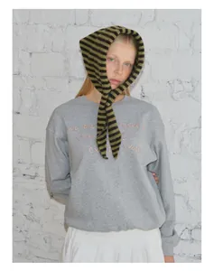 Détail d'une écharpe en laine rayée vert et noir avec un sweat-shirt gris brodé de qualité