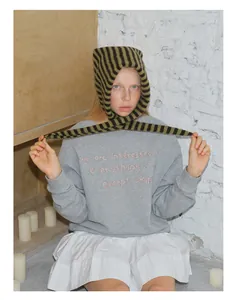 Détail d'une écharpe en maille rayée en laine de qualité et un sweat gris en coton