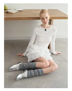 Detail of balletcore outfit featuring grey knitted leg warmers and silver lace-up shoes