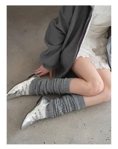 Detail of grey knitted leg warmers paired with silver mirror pointed-toe ballet flats