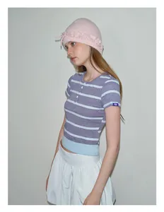 Detail of pink knitted beanie with ruffle trim and striped polo crop top for women