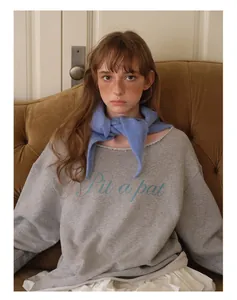 Détail d'un foulard triangulaire bleu en laine mélangée porté en châle sur un sweat-shirt