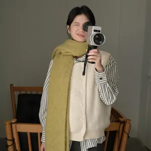 Mustard green thick wool scarf with tassels paired with a beige knit vest and striped shirt