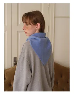 Détail d'un foulard triangulaire bleu en laine sur un sweat-shirt gris à manches