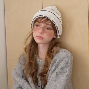 Minimalist white knit beanie with black stripes for women shown on a model