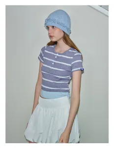 Detail of light blue knitted beanie with ruffle trim paired with a striped shirt