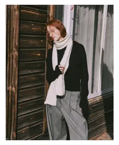 Detail shot of woman wearing a cozy off-white cable knit wool scarf in an outdoor setting