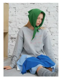 Detail of green knit wool triangle scarf paired with grey embroidered sweatshirt