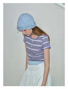 Detailed texture of light blue knit wool beanie with ruffle edge and bow accent