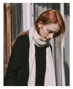 Detailed texture of thick cream cable knit wool blend scarf on a soft black sweater
