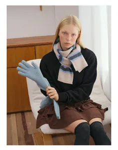 Close-up of light blue knit gloves and striped wool scarf with textured winter patterns