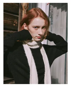 Close-up of cream cable knit wool scarf paired with a black sweater for winter warmth