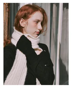 Detailed close-up showing texture of thick cream wool blend knit scarf in warm sunlight