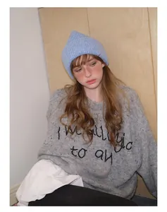 Close-up of light blue knit beanie paired with a gray alpaca blend letter sweater