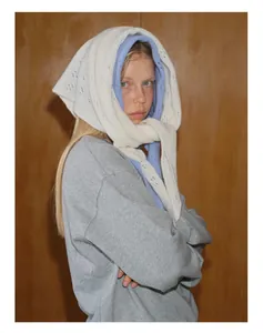 Détail d'un foulard triangle en laine crochetée blanche porté avec un sweat gris