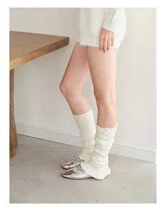 Detail of cream knit leg warmers with ribbed texture and ballet style ruffled hem