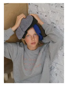 Detail of wool blend knit beanies in assorted colors with a textured grey sweatshirt