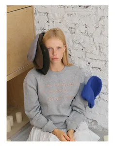 Close-up of soft knitted wool blend beanie with delicate embroidered details on sweatshirt