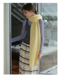 Detailed knit texture of a yellow wool scarf paired with a grey top and patterned skirt