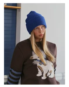 Detail of royal blue knit beanie with wool blend texture and striped sweater cuff