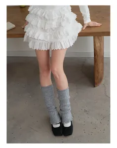 Macro view of grey knit wool leg warmers and white lace tiered skirt for balletcore style