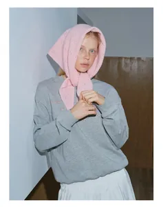 Détail d'un foulard triangle en tricot rose associé à un sweat à col rond gris chic